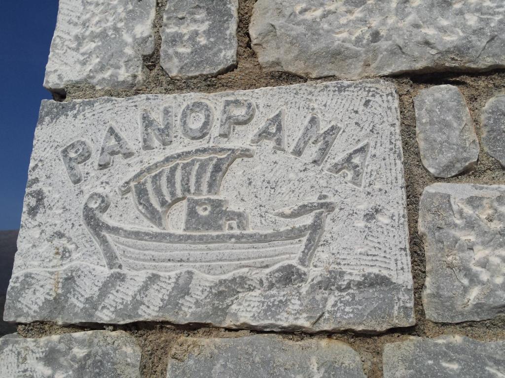 Σκαλισμένη πέτρινη πινακίδα «ΠΑΝΟΡΑΜΑ» με παραδοσιακό καΐκι, στον τοίχο του Panorama Rooms στον Διρό